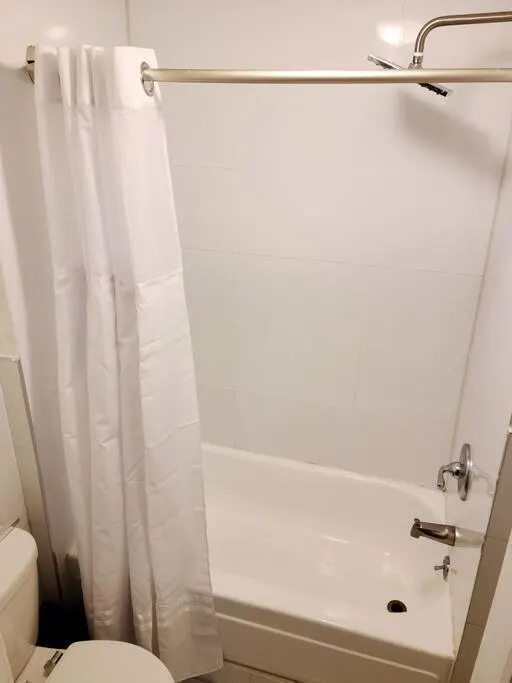 Clean white bathtub with shower.