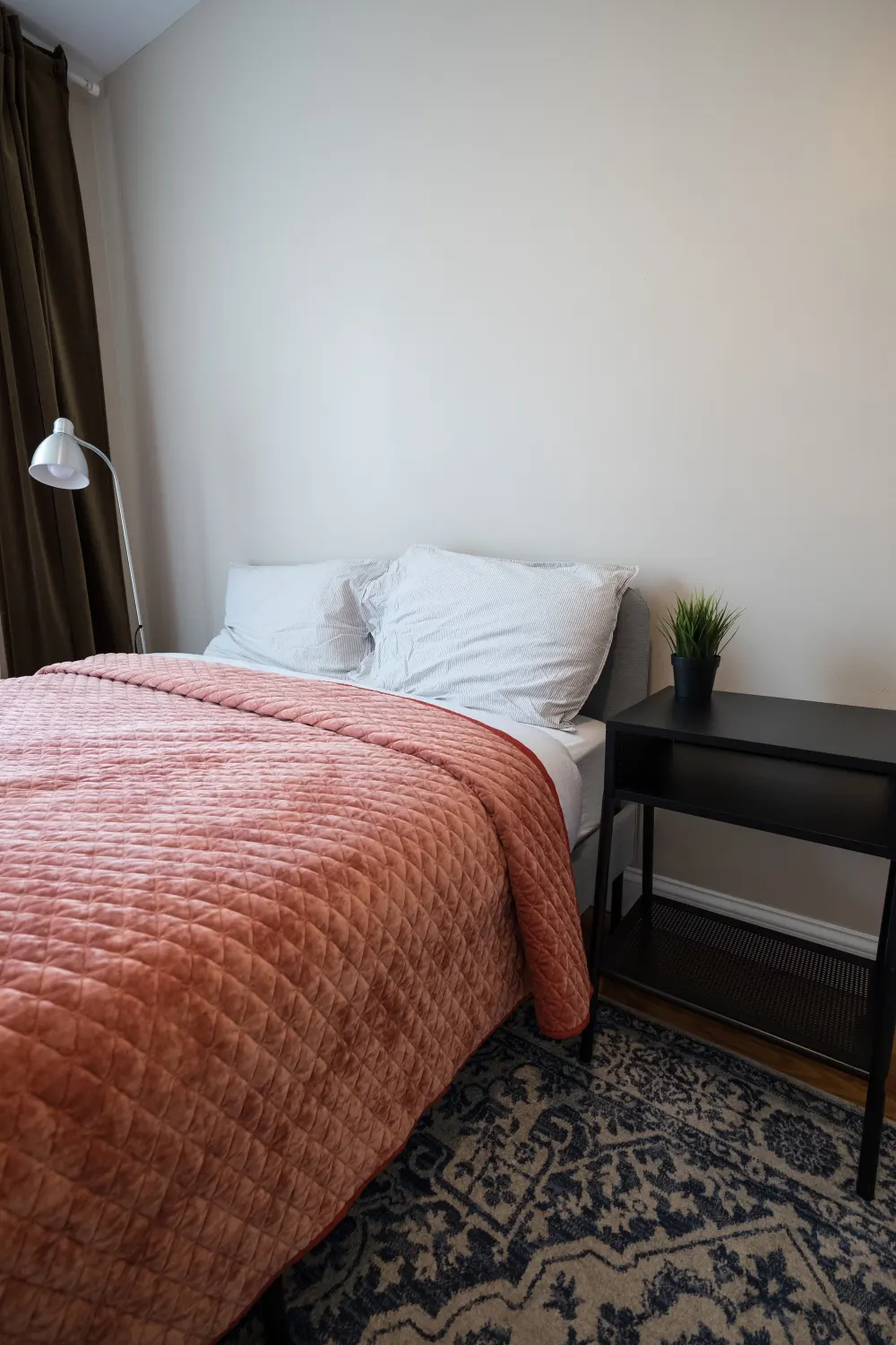 Cozy bedroom with pink bedspread.