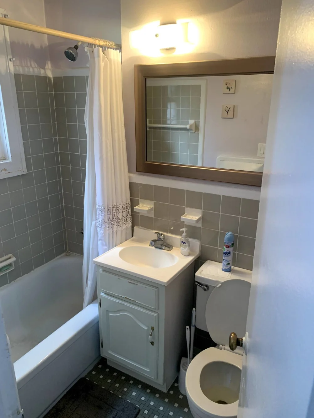 Small, clean, tiled bathroom with bathtub.