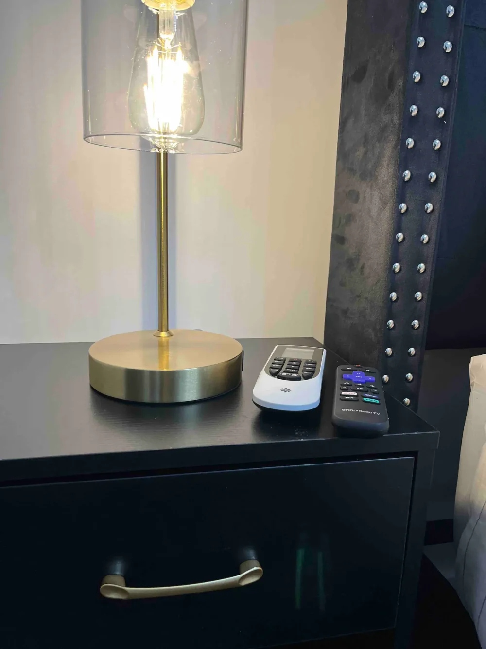Modern lamp and remotes on nightstand.