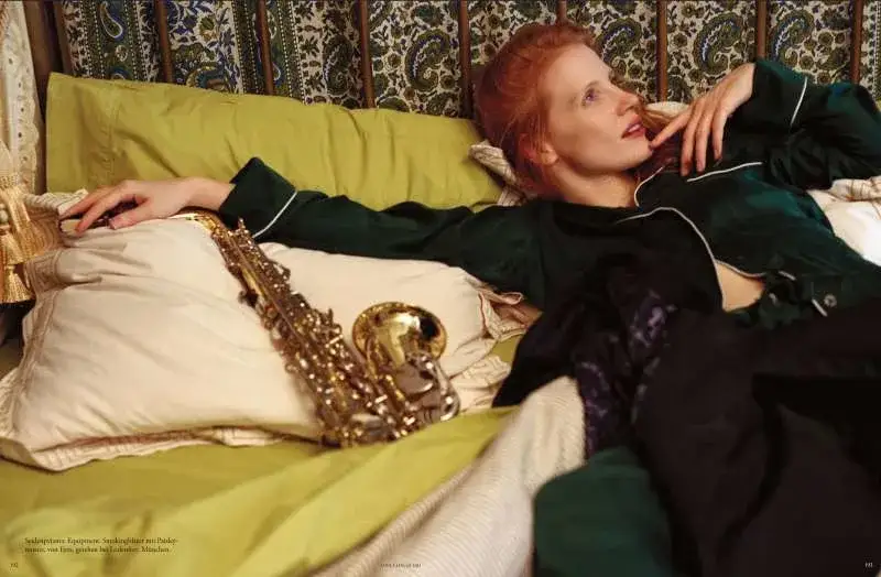 Red-haired woman reclining beside saxophone