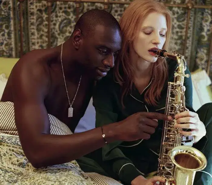 People sharing saxophone in bed