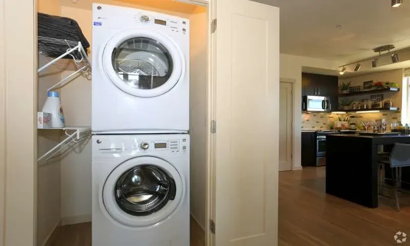 Stacked washer-dryer beside modern kitchen