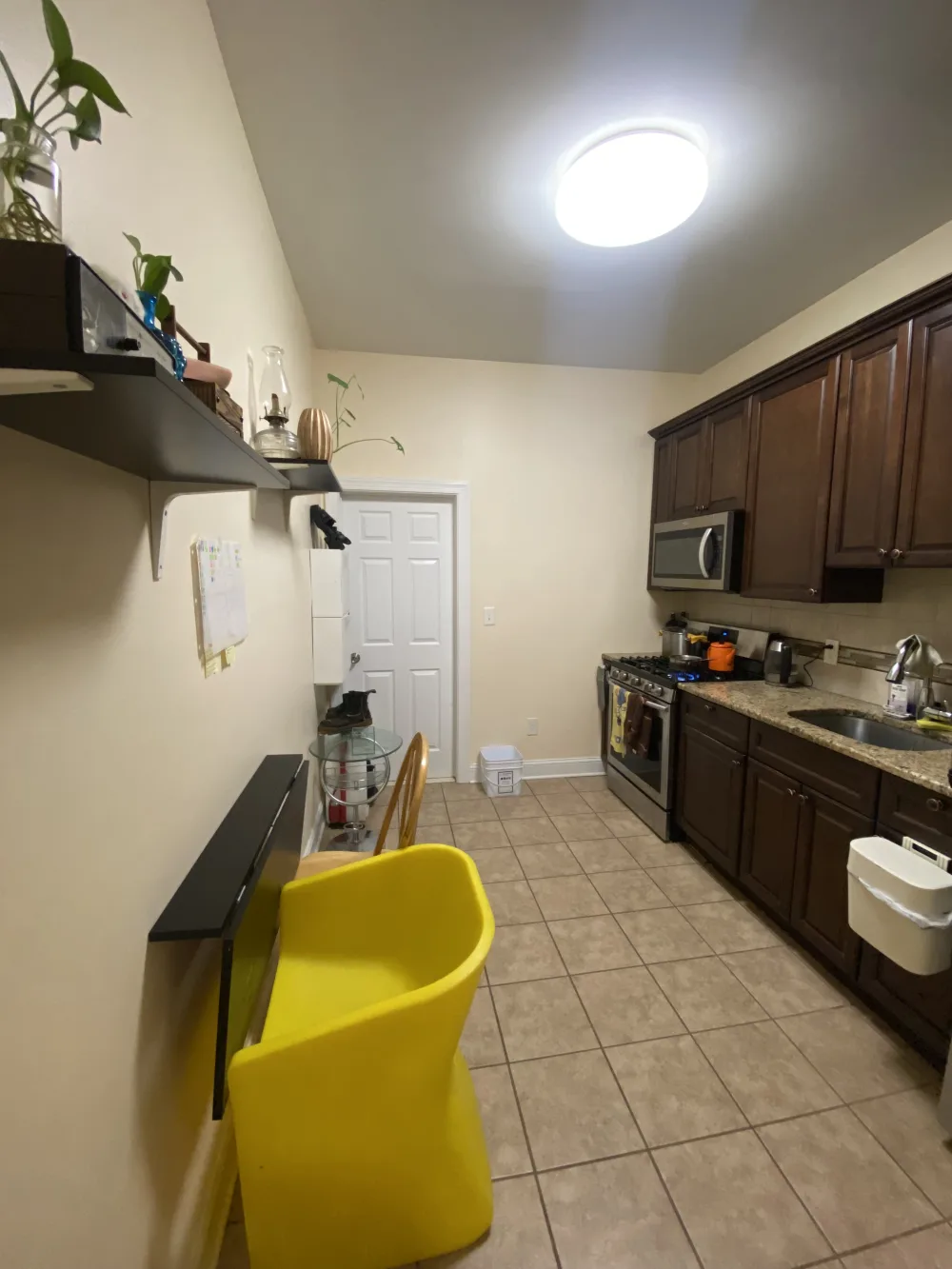 Compact kitchen with yellow chair.