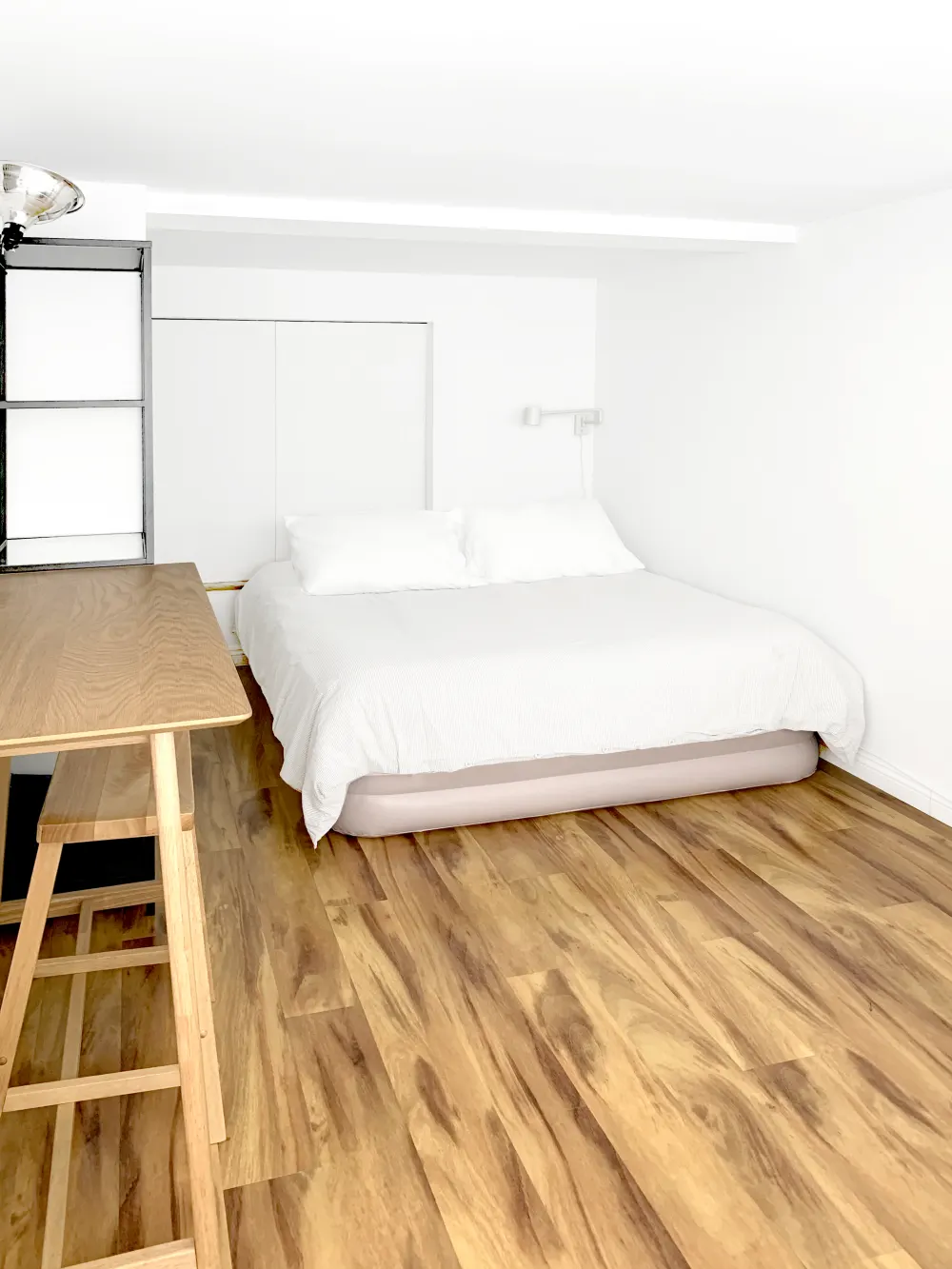 Bright minimalist bedroom with wooden flooring.