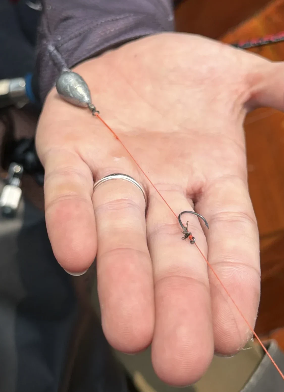 Close-up of a shrimp fishing rig with a sinker, leader line, and hook resting in an angler’s hand.