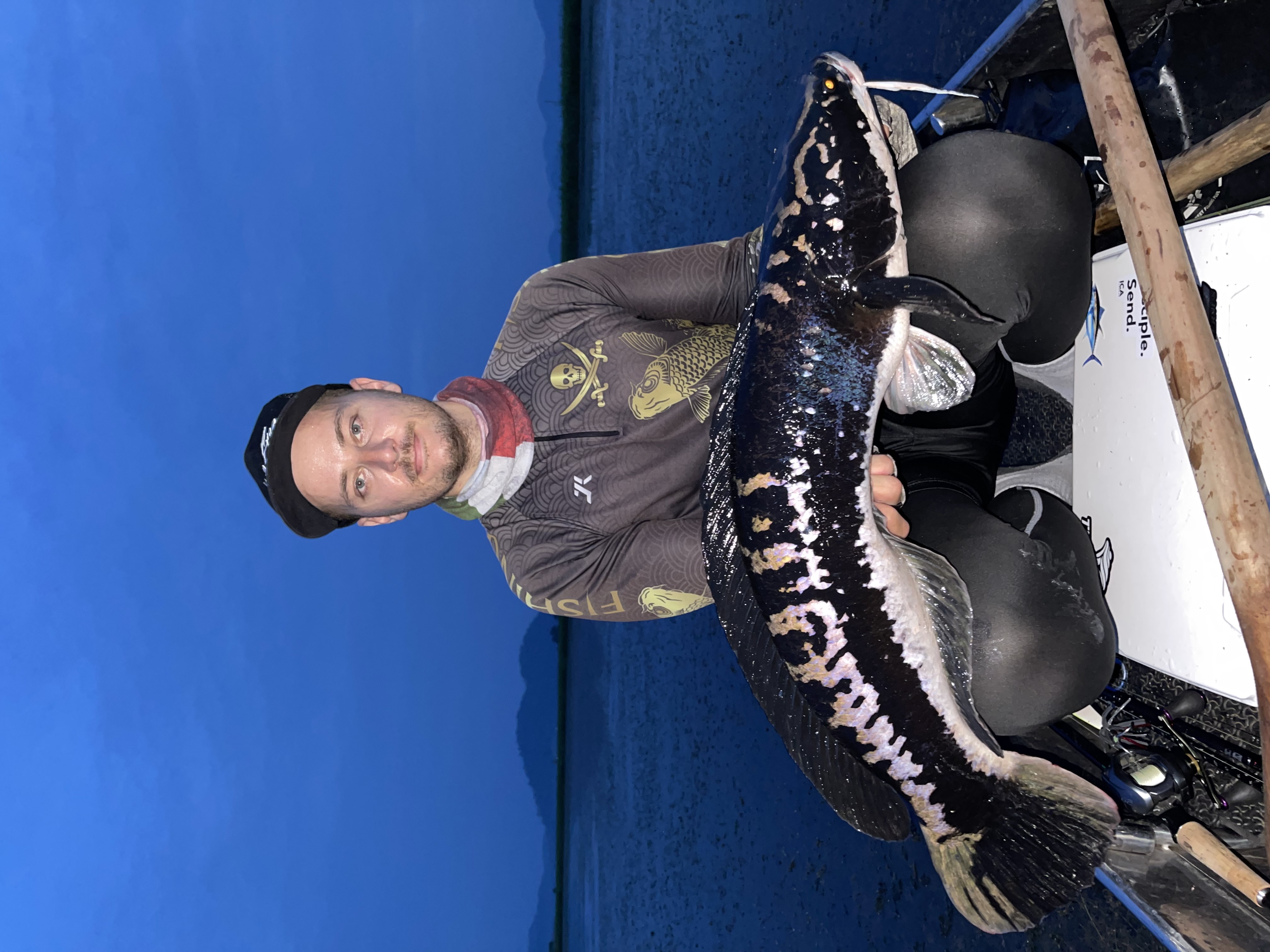 Josh holding a large giant snakehead from a boat in Thailand at blue hour