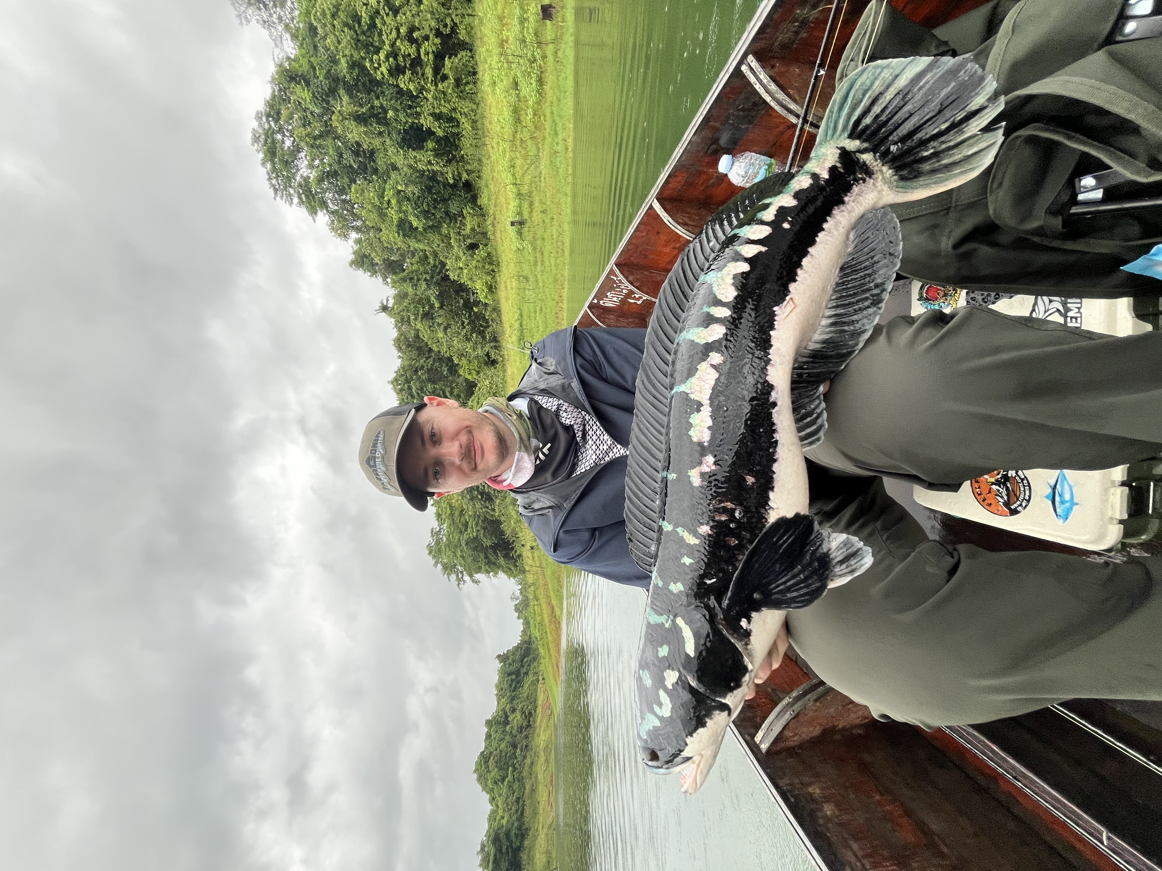 Josh holding a giant snakehead on a rainy day in Thailand