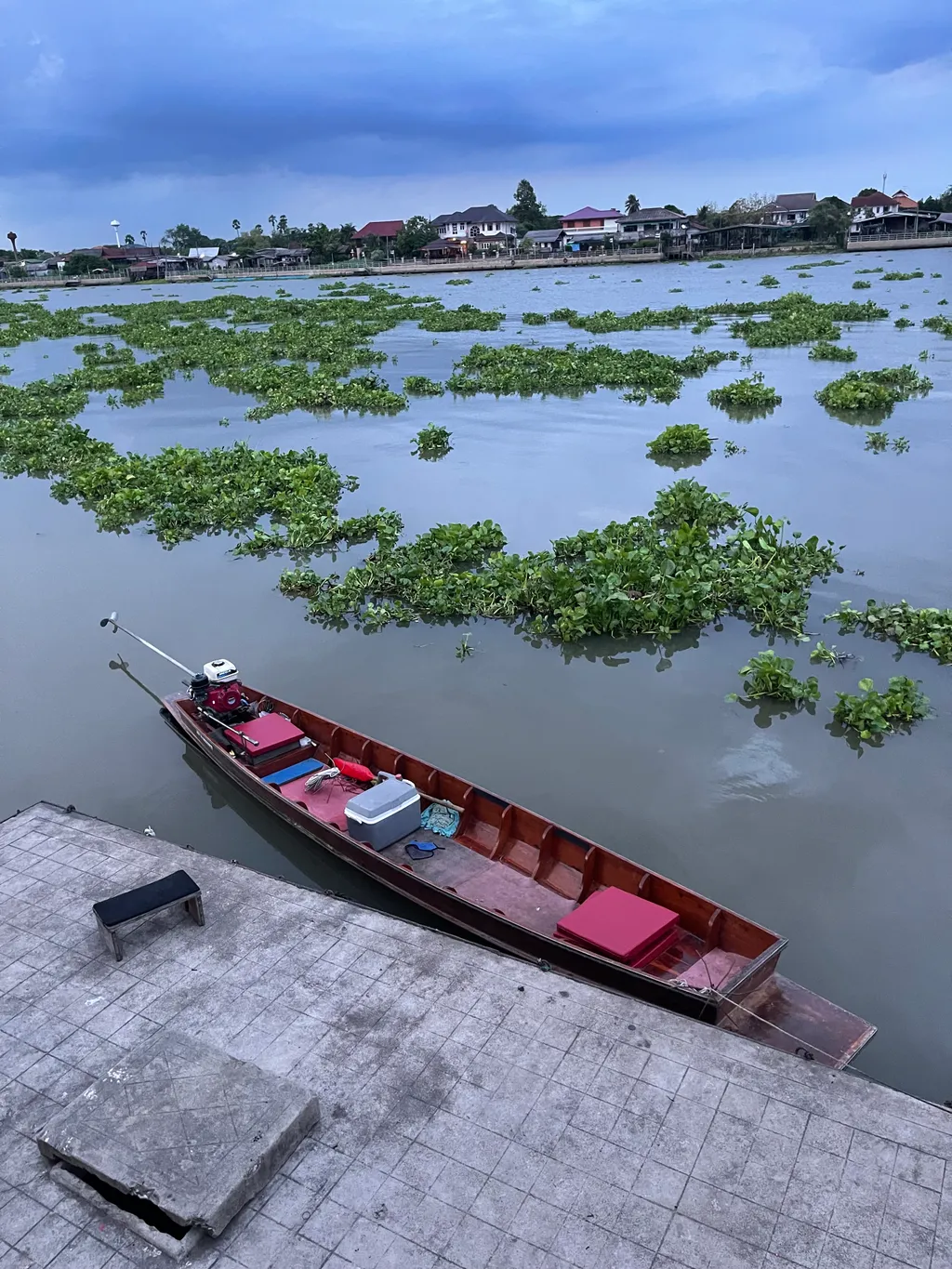 Thai wooden longboat anchored in position for shrimp fishing on the Chao Phraya River at night.