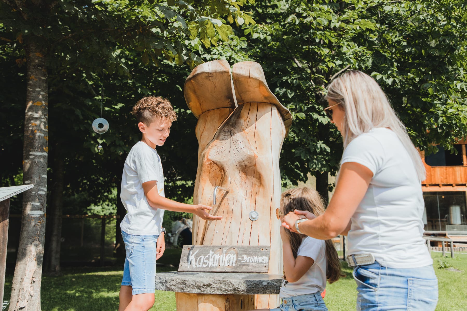 Zwei Kinder mit Mama beim Vitalpinum Kastanienbrunnen