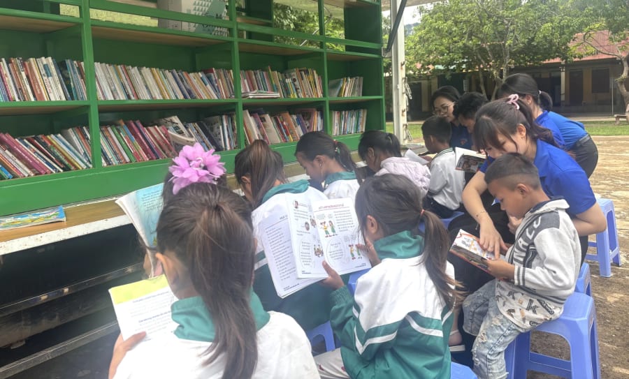 Đoàn viên thanh niên hướng dẫn các em học sinh đọc sách tại thư viện lưu động - Ảnh: K.H