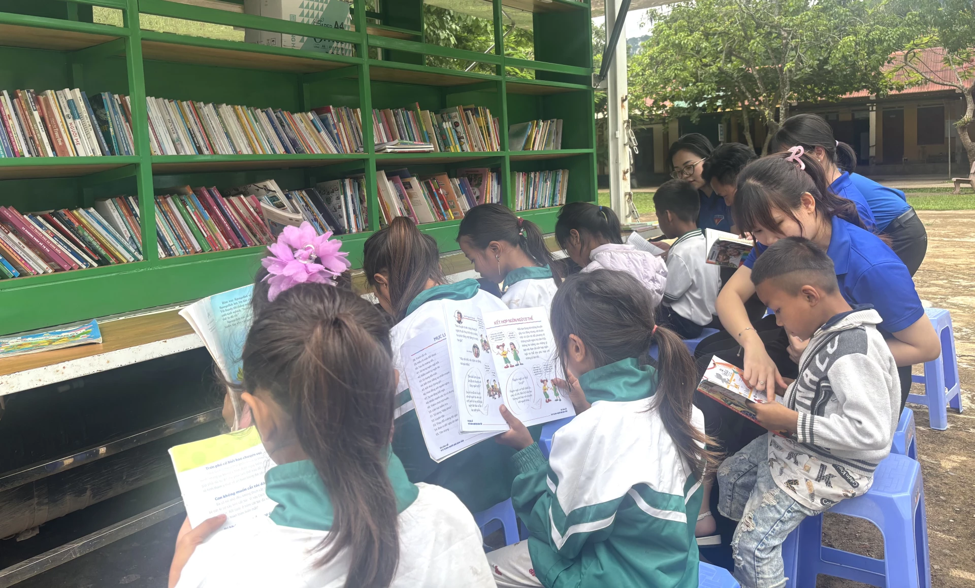 Đoàn viên thanh niên hướng dẫn các em học sinh đọc sách tại thư viện lưu động - Ảnh: K.H