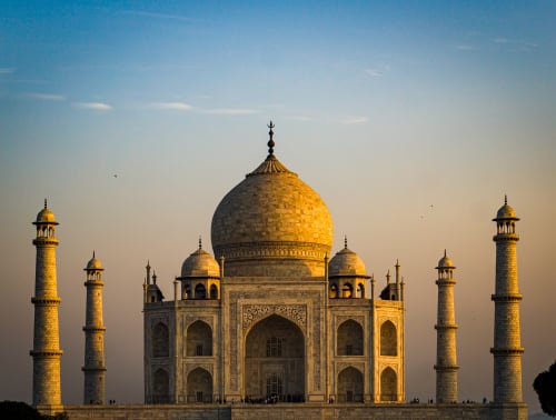 The iconic Taj Mahal captured during golden hour sunrise with warm light illuminating the marble structure