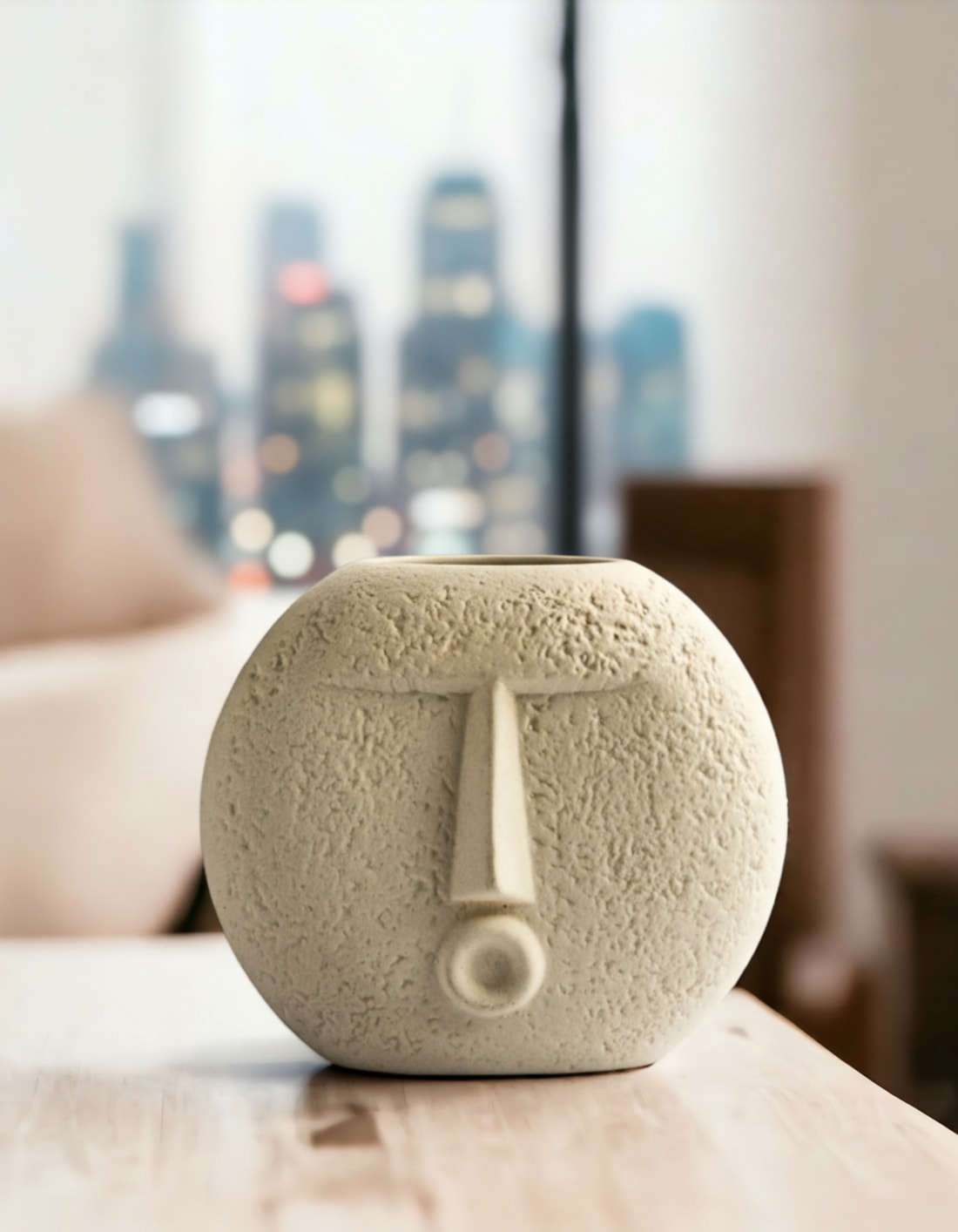 Modern off-white ceramic vase with a textured abstract face design placed on a wooden surface.