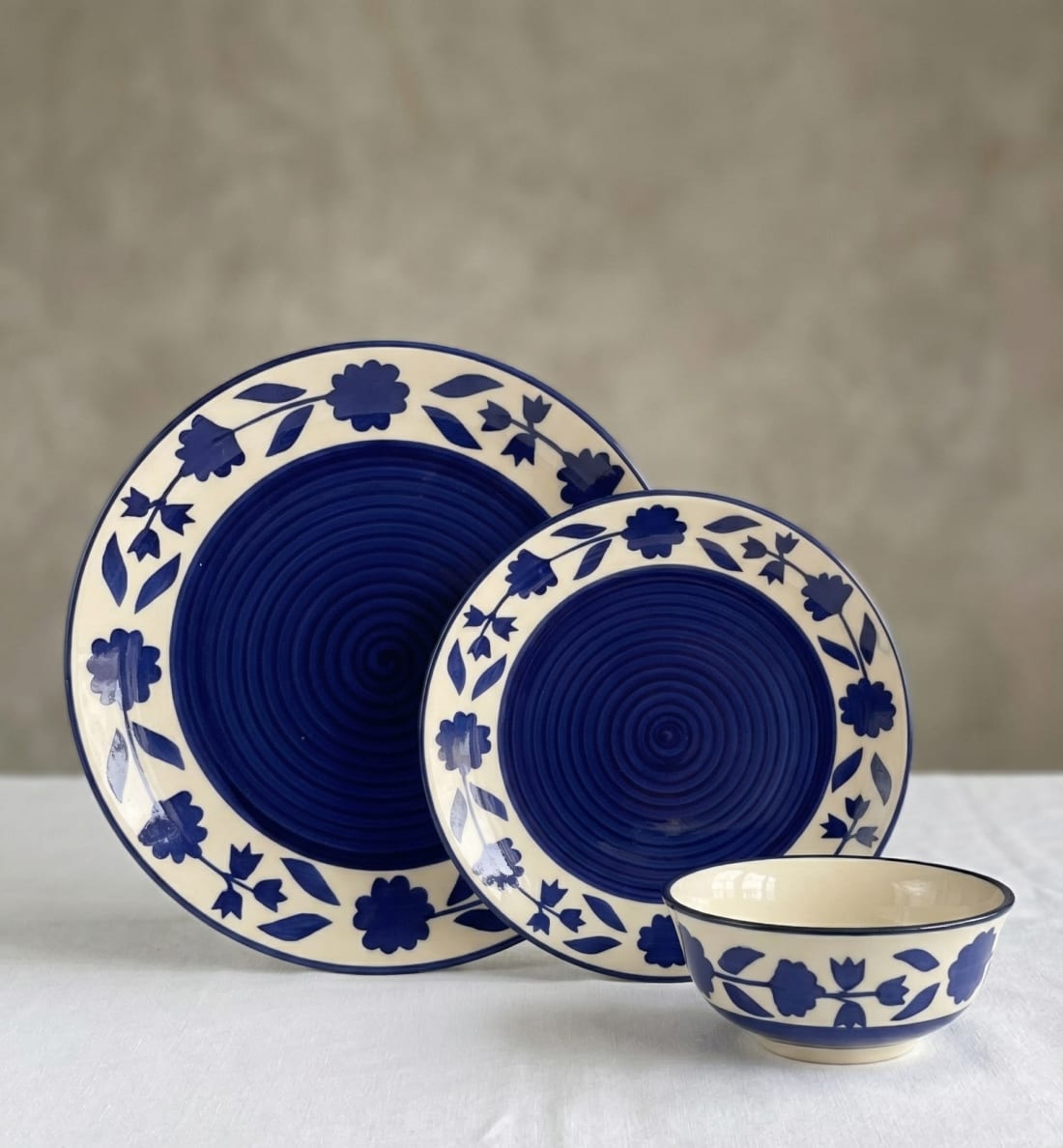 3-piece blue and white hand-painted ceramic dinnerware set with floral border and spiral center pattern.