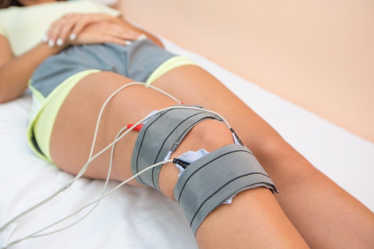 Sedyede uzanan kişinin dizinin üstüne ve altına bantlarla yerleştirilmiş elektrot pedleri