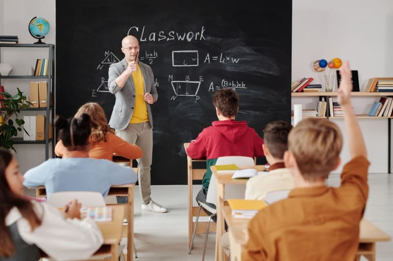 A teacher writing on a chalkboard in a classroom