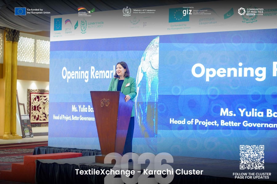Yulia speaking at a podium during TextileXchange 2026, with the conference screen, event branding and partner logos visible behind her.