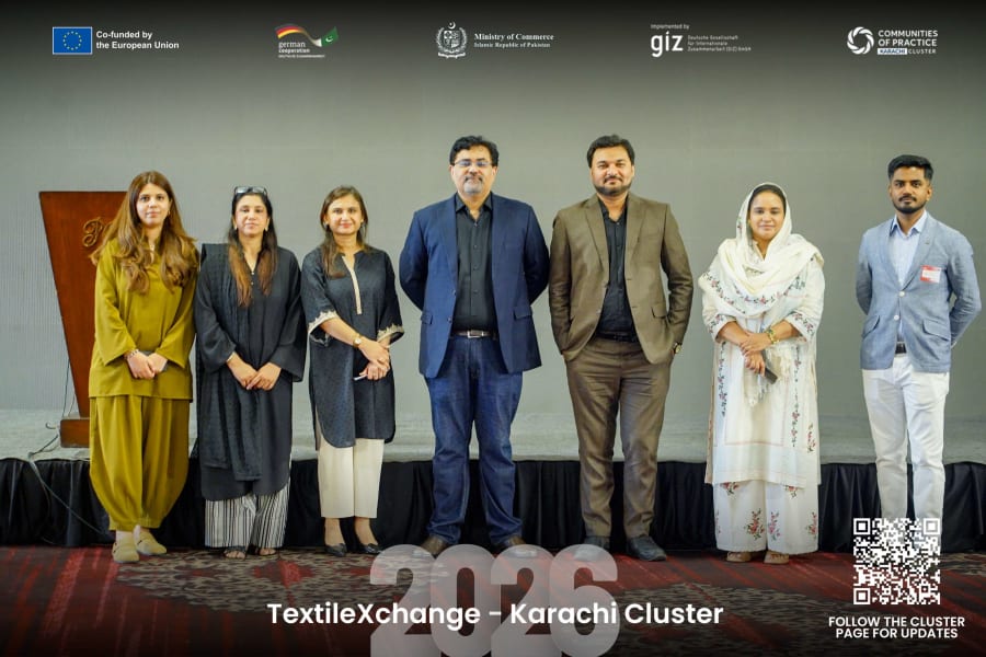 Karachi Cluster team members standing together for a group photo at TextileXchange 2026, with event branding and partner logos visible.
