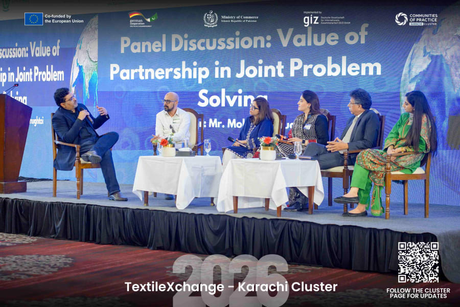 Mobeen Chughtai moderating a panel discussion at TextileXchange 2026, with panellists seated on stage in front of a screen reading Value of Partnership in Joint Problem Solving.