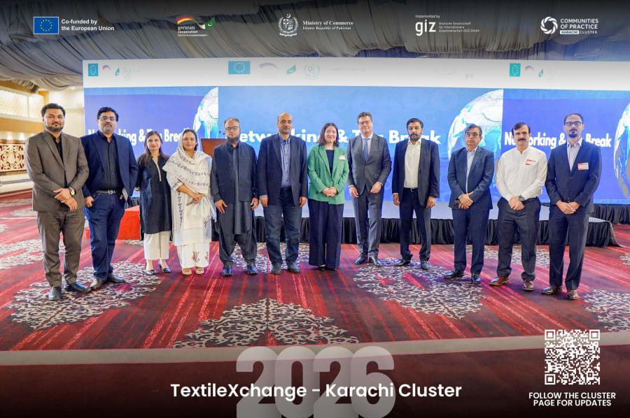 Group photo of the GIZ team and Karachi Cluster team standing with the German Consul General on the TextileXchange 2026 stage in Karachi.