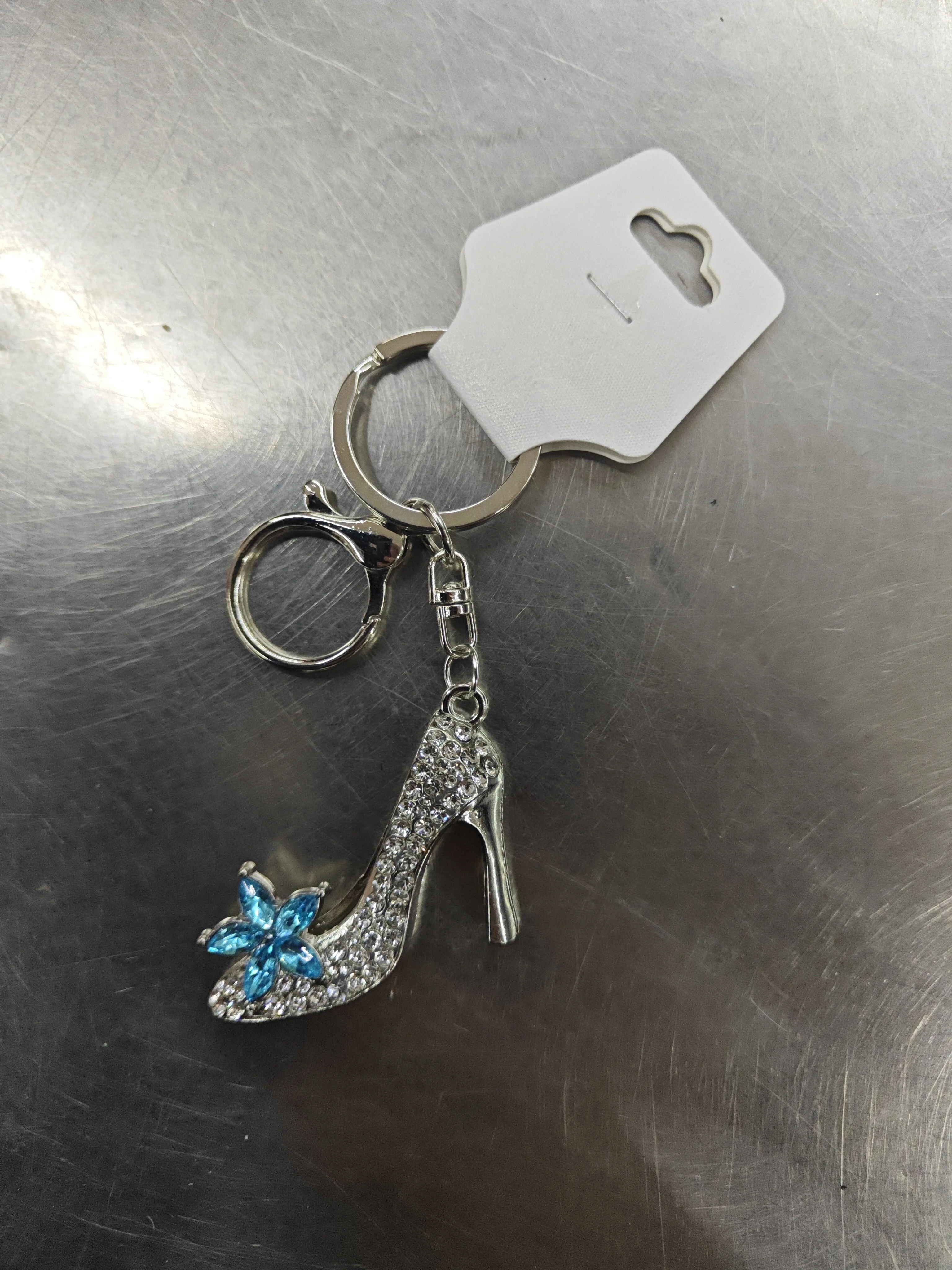 Porte-clés chaussure à talon argentée avec strass et fleur bleue