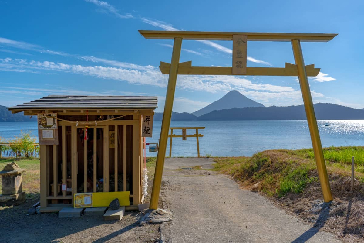 Scenic lakeside viewpoint featuring a handmade golden torii and volcanic mountain backdrop