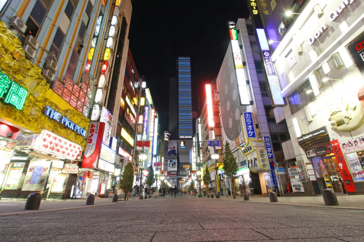 Neon-lit street in Shinjuku with the Godzilla head towering above
