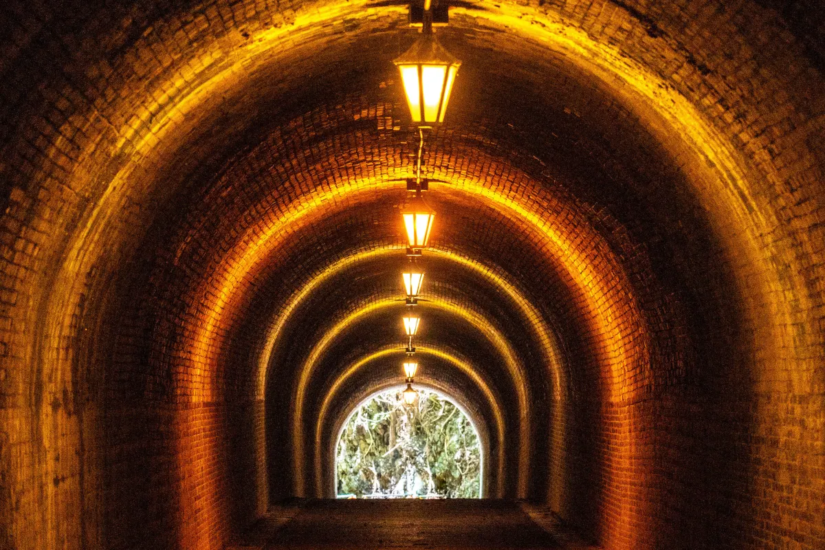 Historic red brick tunnel at Utsunoya Pass with arched ceiling, softly lit interior, and a narrow pedestrian path stretching through a quiet mountain setting in Japan.