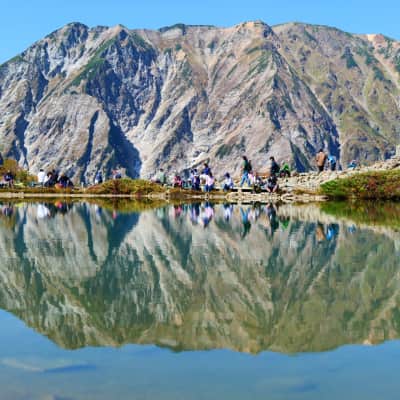 Happo Pond reflecting the peaks of the Hakuba Northern Alps beneath a clear blue sky in Nagano, Japan.