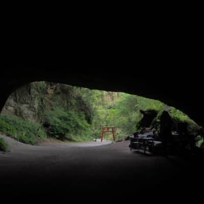 Entrance of Mizonokuchi Cave featuring a red torii gate surrounded by lush forest in Kagoshima, Japan
