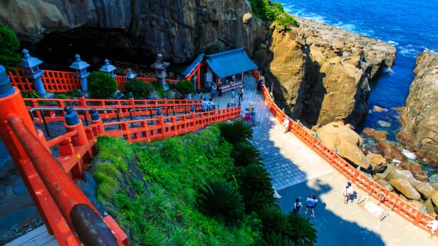 Stone pathway leading to Udo Shrine beneath rugged seaside cliffs.