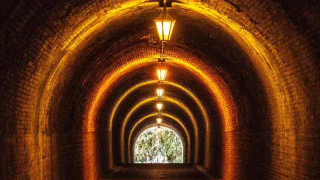 Historic red brick tunnel at Utsunoya Pass with arched ceiling, softly lit interior, and a narrow pedestrian path stretching through a quiet mountain setting in Japan.