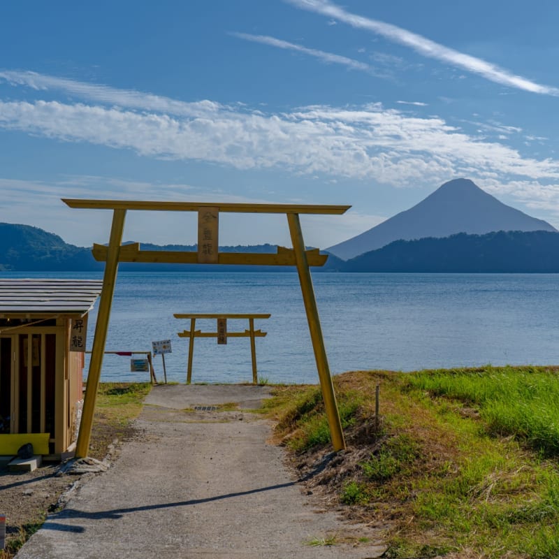 Golden torii gate overlooking Lake Ikeda and Mount Kaimon in Kagoshima