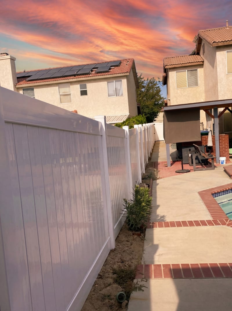 White vinyl privacy fence along a side yard next to a pool