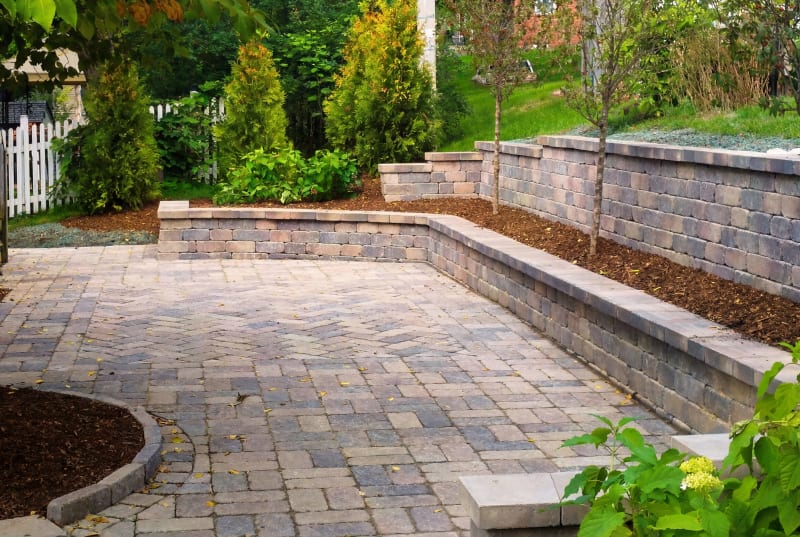 Paver patio with a curved seat wall and garden beds