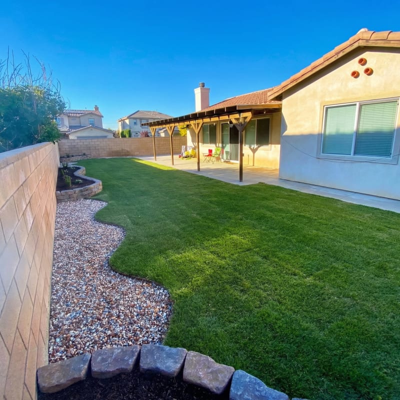 Artificial turf lawn with a curved gravel border along a block wall