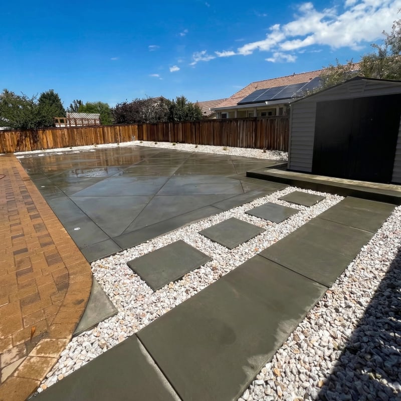 New concrete patio with stepping pads in white rock and a brick border