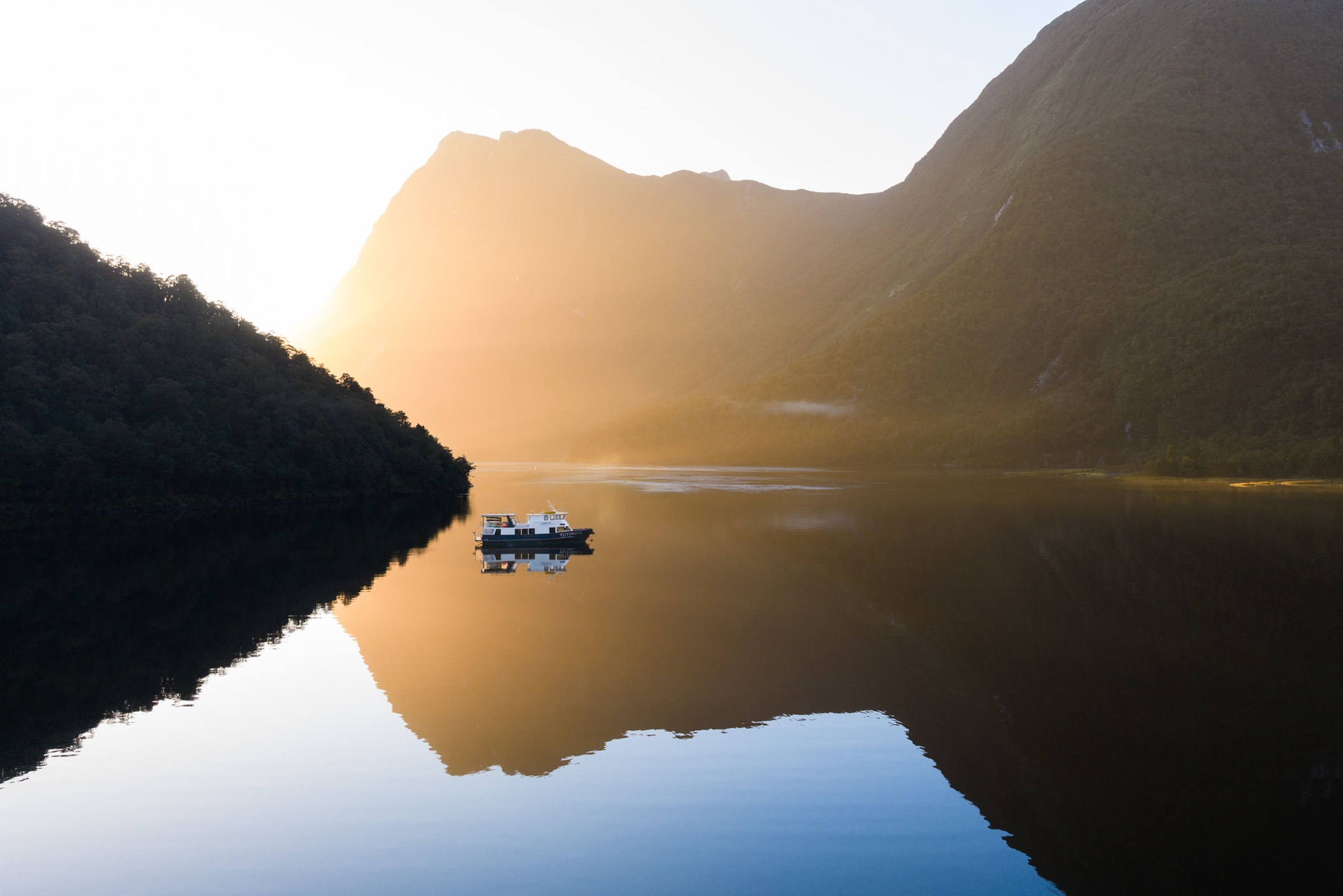MV Tutoko II at sunrise reflected in Doubtful Sound mist, Fiordland Expeditions