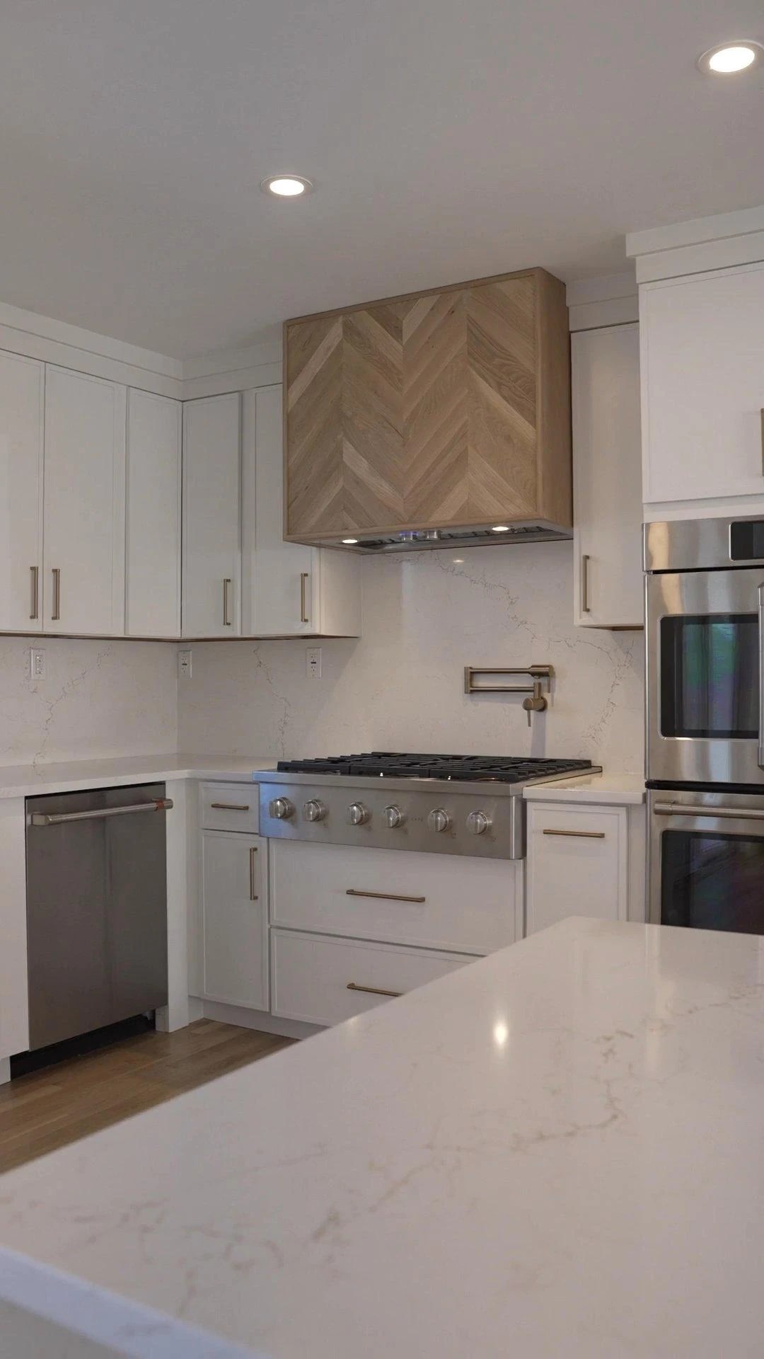 White kitchen cabinetry and custom range hood in Plainview
