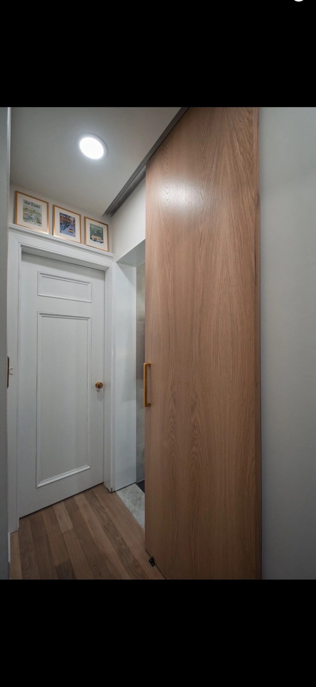 Custom fabricated white oak full height recessed barn door to bathroom with polished grass hardware