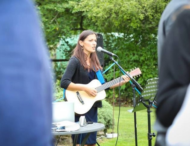 nina playing guitar and singing at an outdoors wedding ceremony