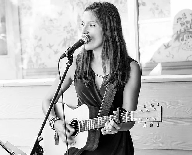 black and white photo of nina singing and playing guitar