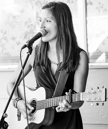 black and white photo of nina singing and playing guitar