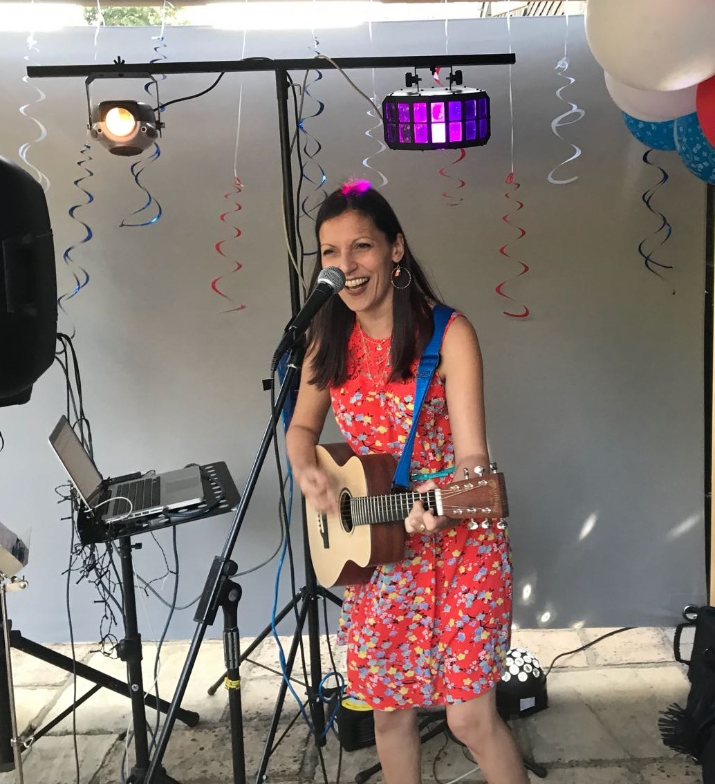 image of nina singing and playing guitar at a drinks reception