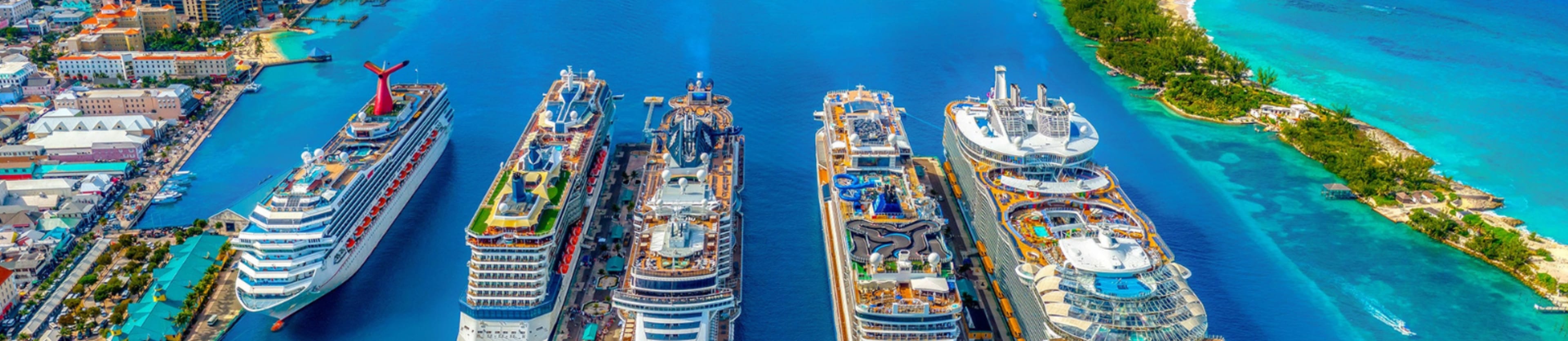 A vibrant aerial view of a bustling cruise ship port surrounded by crystal-clear turquoise waters and lush green landscapes.