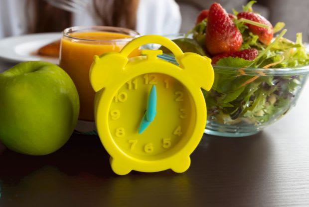 table with a yellow alarm clock and healthy food