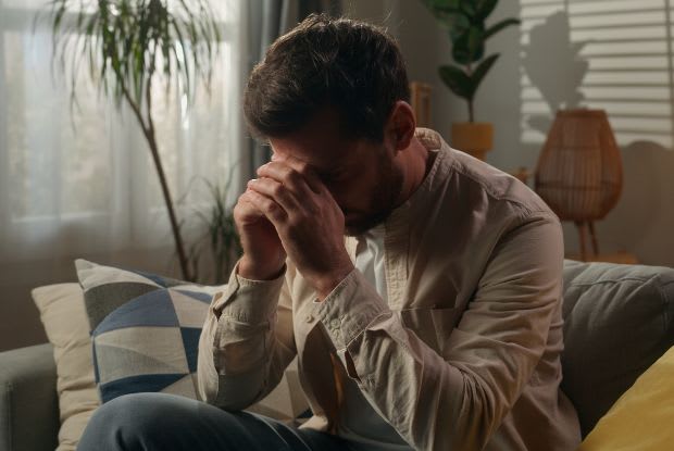 A stressed man sitting on the couch