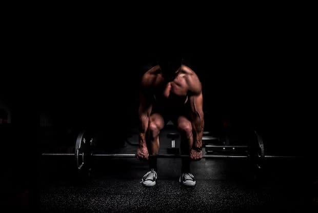 a muscled man picking up a weight bar