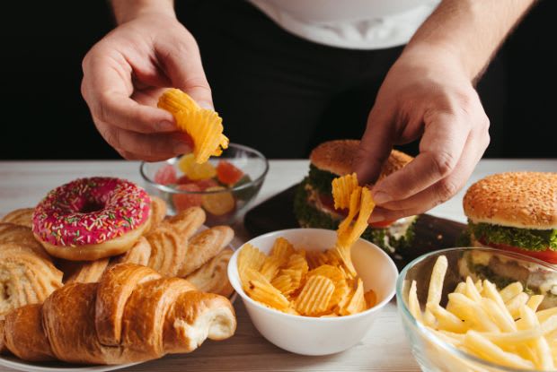 A man grabbing chips from a table of fast food